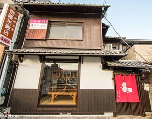 A traditional Japanese building with a wooden exterior, a tiled roof, and a large window.