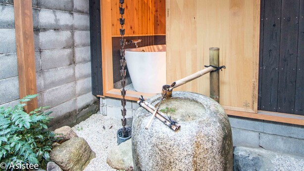 Een traditionele Japanse wasbak met een stenen kom en houten constructie.