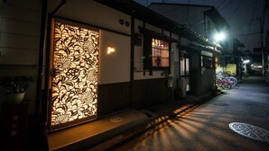 A traditional Japanese building with a decorative paper screen door and a small garden area with a potted plant.