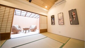 A traditional Japanese room with tatami flooring, a sliding door, and a view of the outside.