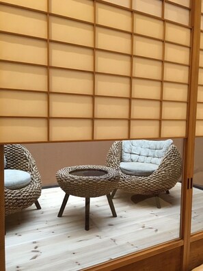 Une pièce dotée d’une porte coulissante de style japonais traditionnel, d’une table ronde en fibres tressées et de deux chaises en fibres tressées.