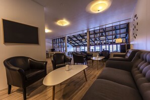 A modern lounge area with leather sofas, a coffee table, and a large blackboard on the wall. - The Northern Comfort Inn (Olafsfjordur)