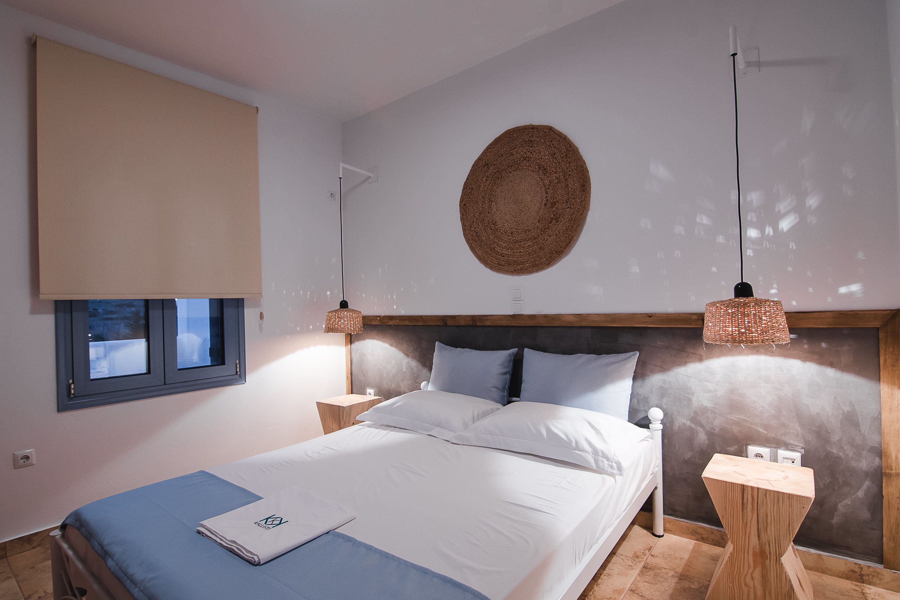 Ein modernes Schlafzimmer mit einem großen Bett, einem runden Wandteppich aus Gewebe und zwei Nachttischlampen.