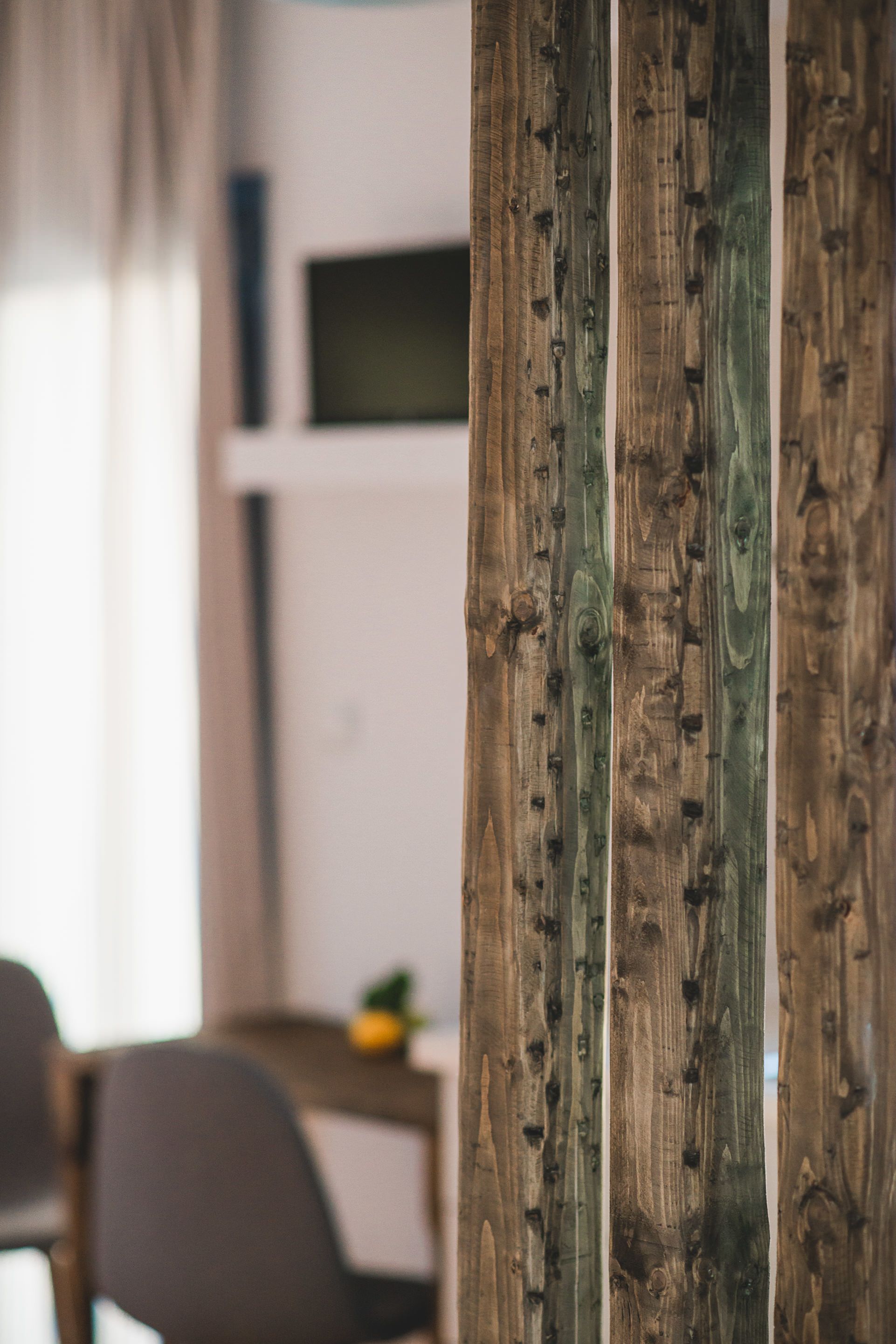 A wooden wall with vertical planks, a white shelf with a television, and a blurred dining area.