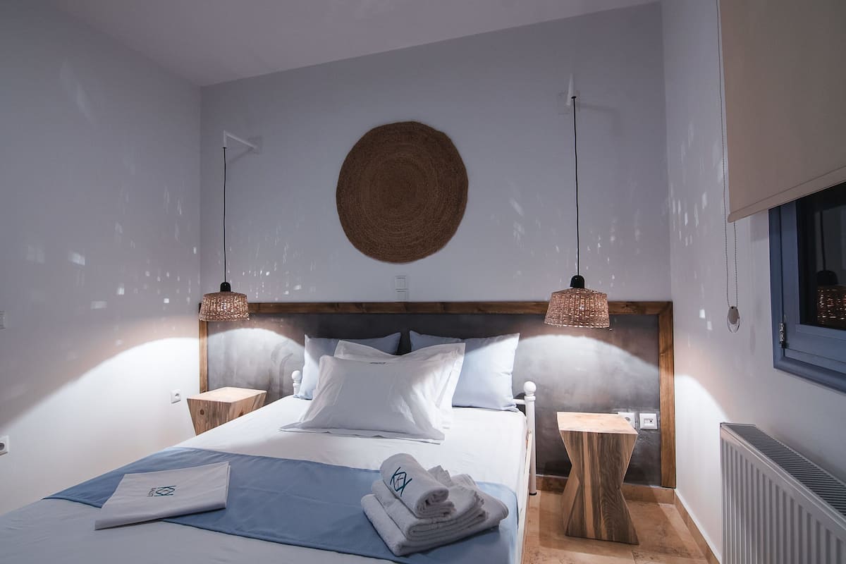 Ein modernes Schlafzimmer mit einem großen Bett, zwei Nachttischen, einer runden Wanddekoration und Pendelleuchten.