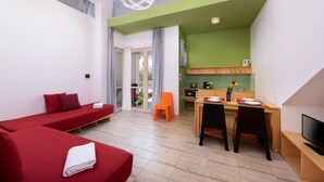 Un appartement moderne avec deux lits rouges, un coin repas et une cuisine.