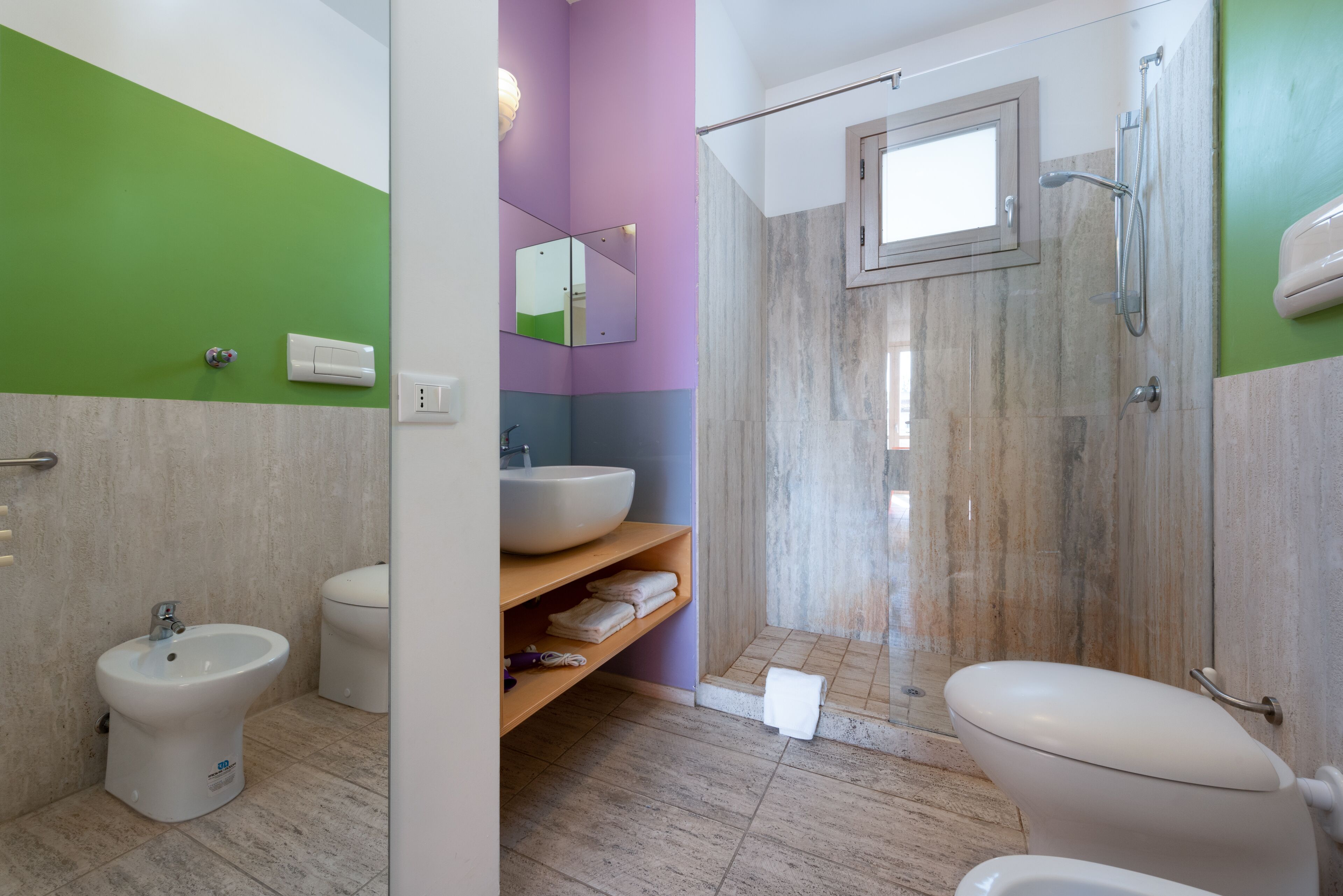 A modern bathroom with a bidet, toilet, and a shower area.