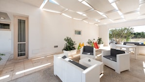 Un espace extérieur aménagé en terrasse, avec des meubles en osier blanc, une plante en pot et une vue sur le paysage environnant.