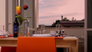 Une table à manger avec une bouteille de vin, un vase de tulipes et des verres à vin.