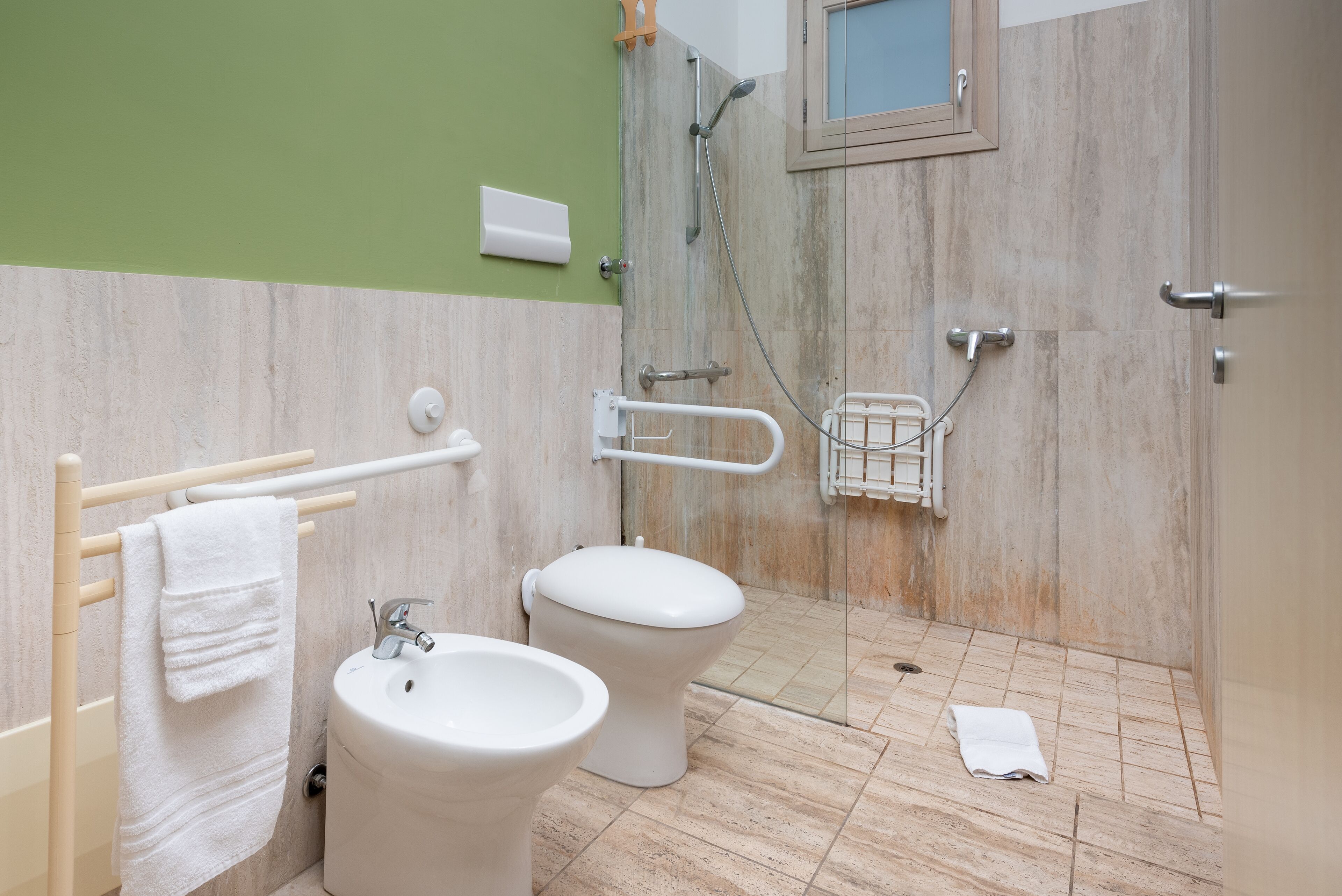 Une salle de bain équipée de toilettes, d’un bidet et d’une barre d’appui.