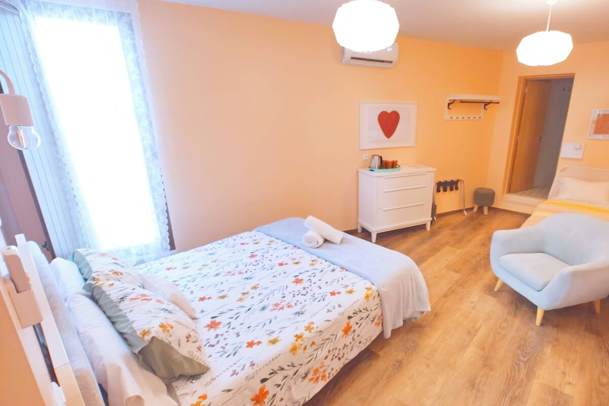 Un dormitorio con cama, una silla, cómoda y puerta.