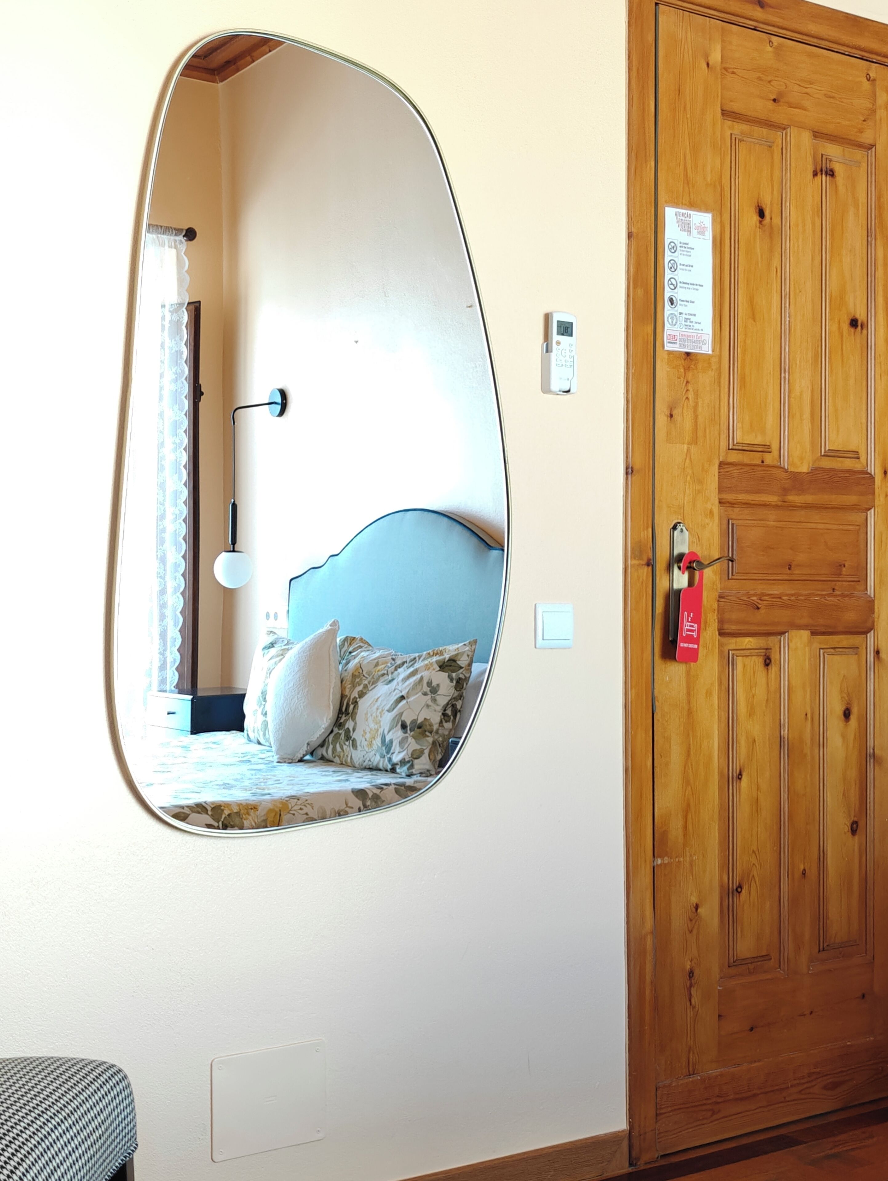 Une chambre à coucher avec un lit, un miroir, une porte en bois et un interrupteur.