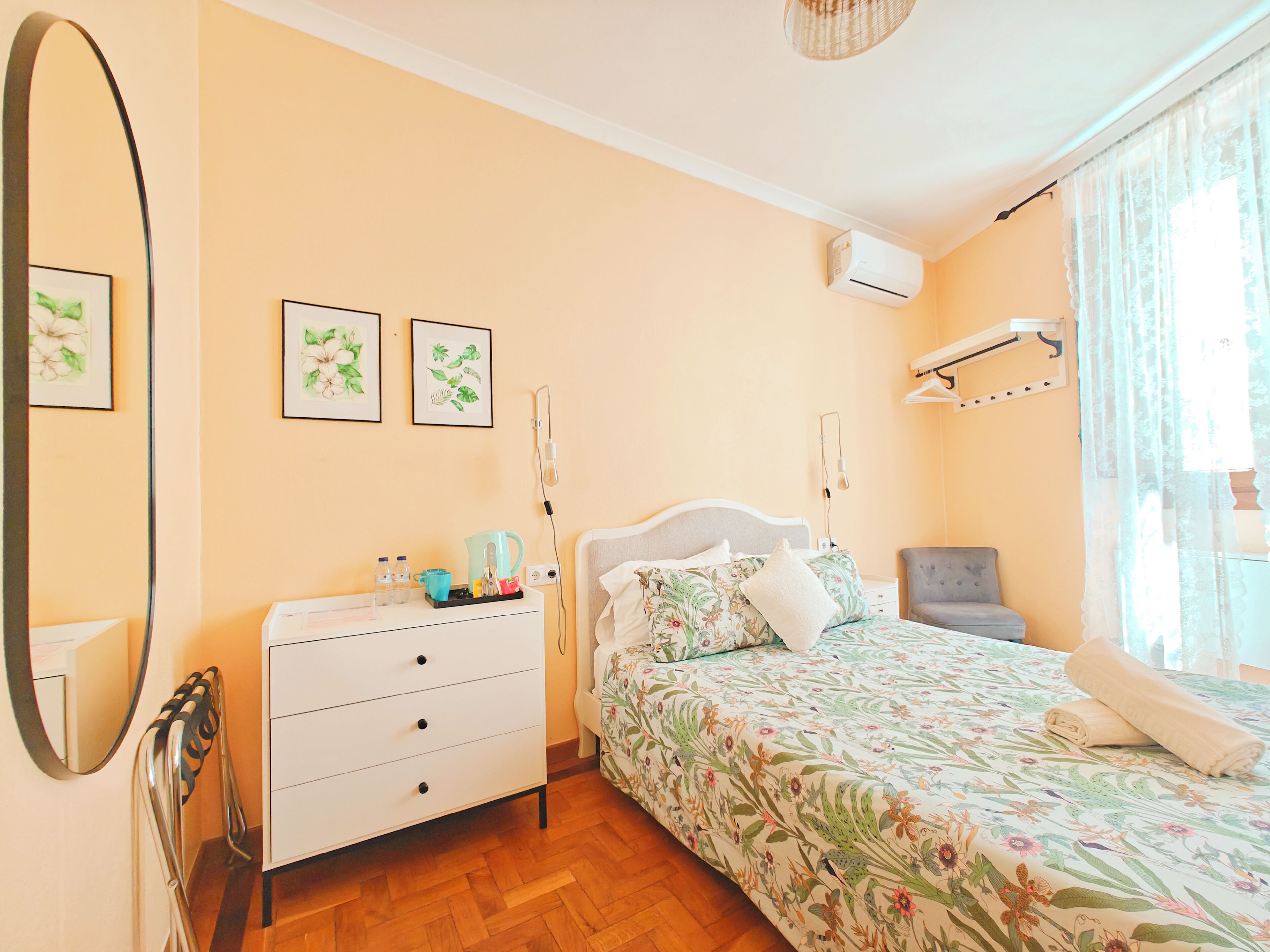 A bedroom with a bed, a dresser, a mirror, and a wall-mounted air conditioner.