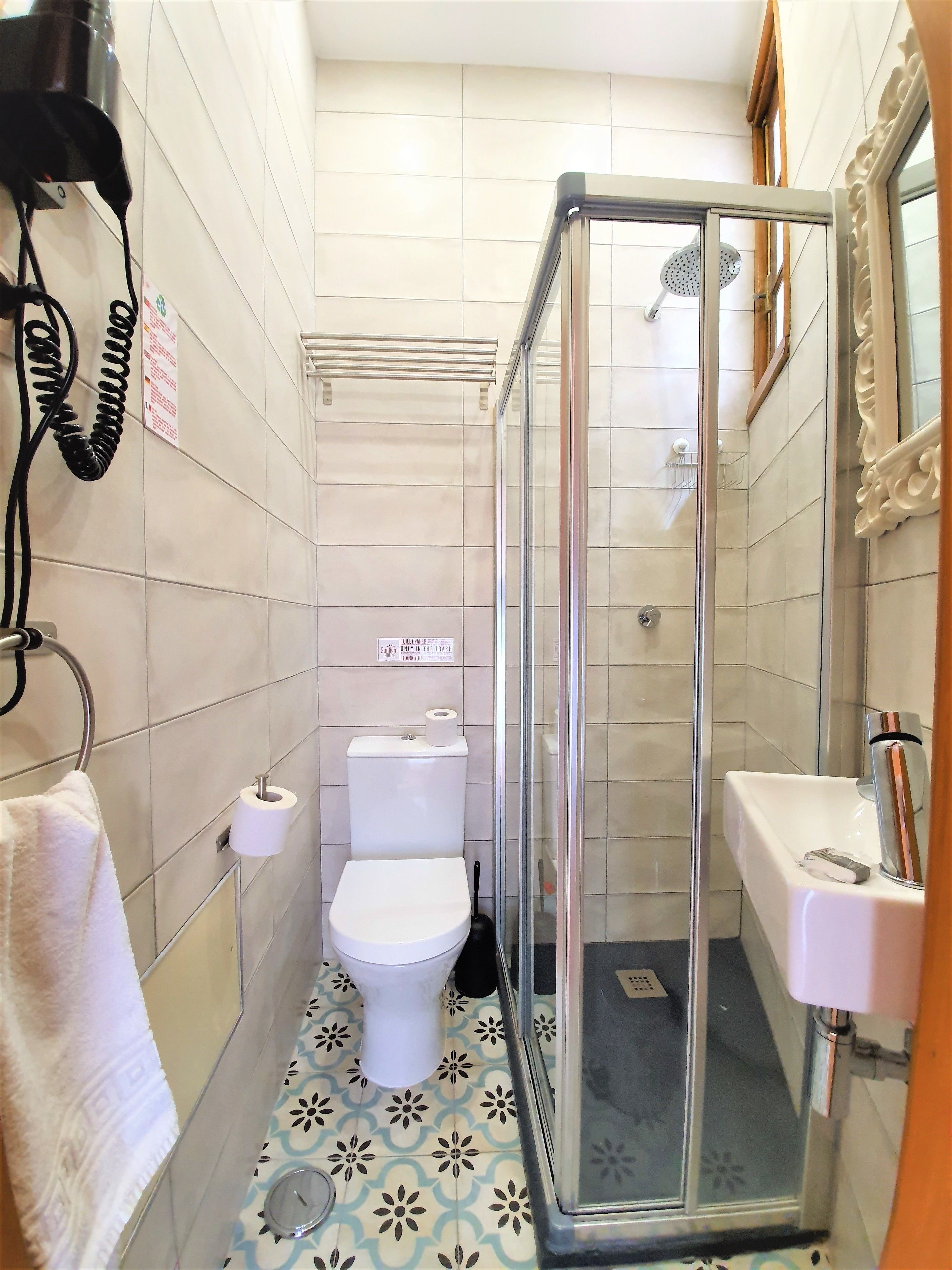 A bathroom with a toilet, a shower with a glass door, a sink, and a towel hanging on a rack.