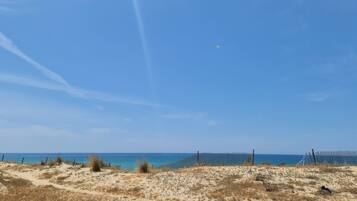 Una spiaggia con una recinzione in legno e dune sabbiose.