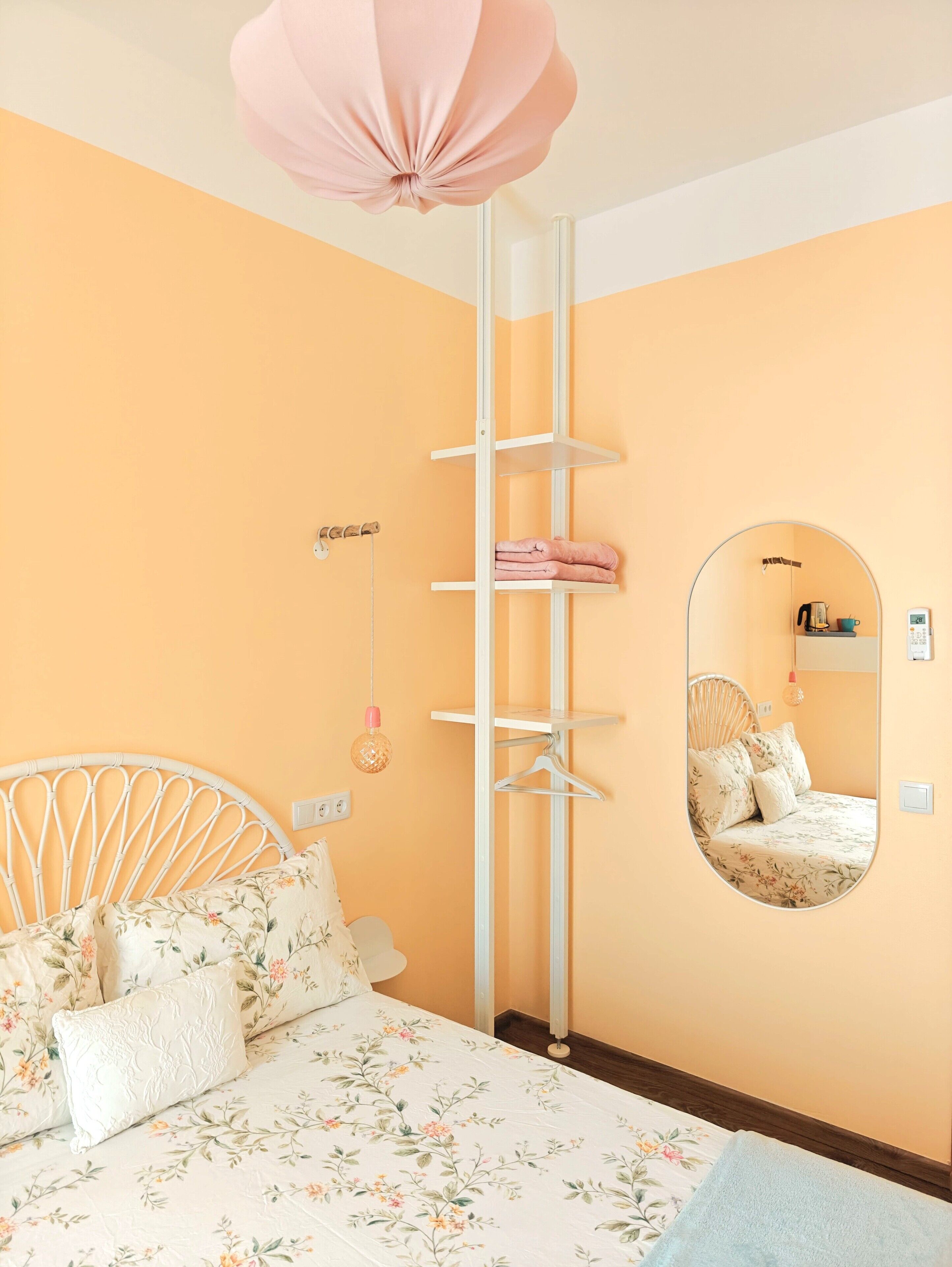 Ein Schlafzimmer mit einem Bett, einer Hängelampe, einem Kleiderschrank, einem Spiegel und einem Nachttisch.