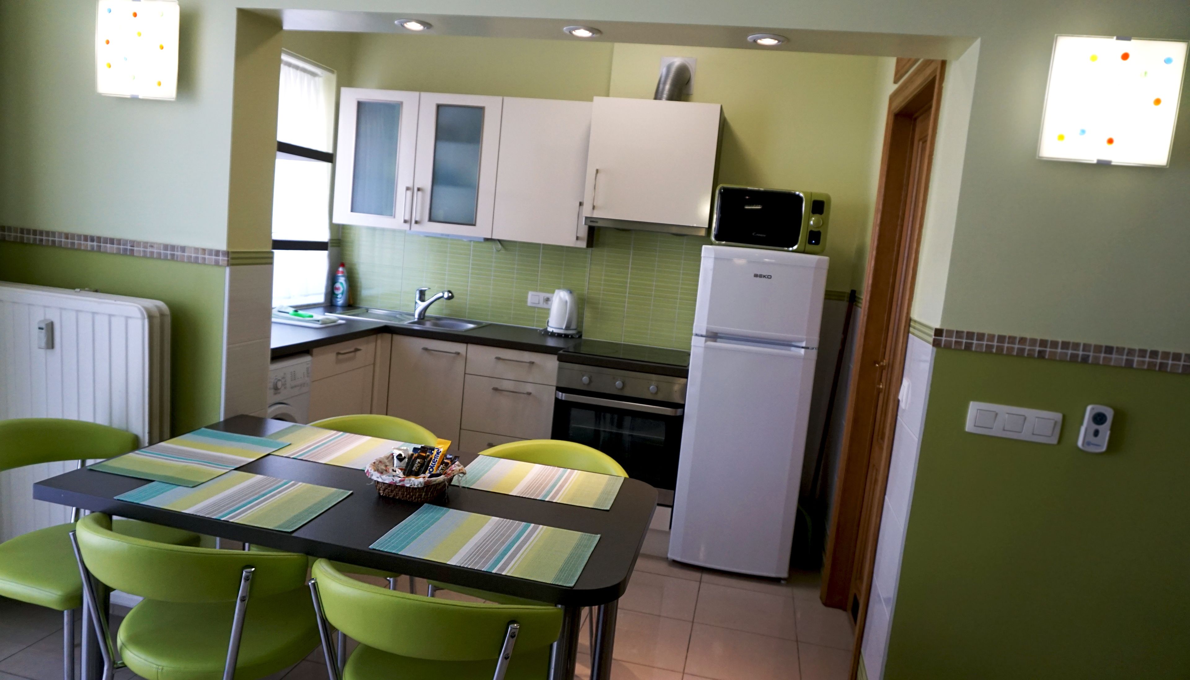 A compact kitchen with a dining area, featuring a refrigerator, stove, microwave, and a sink.