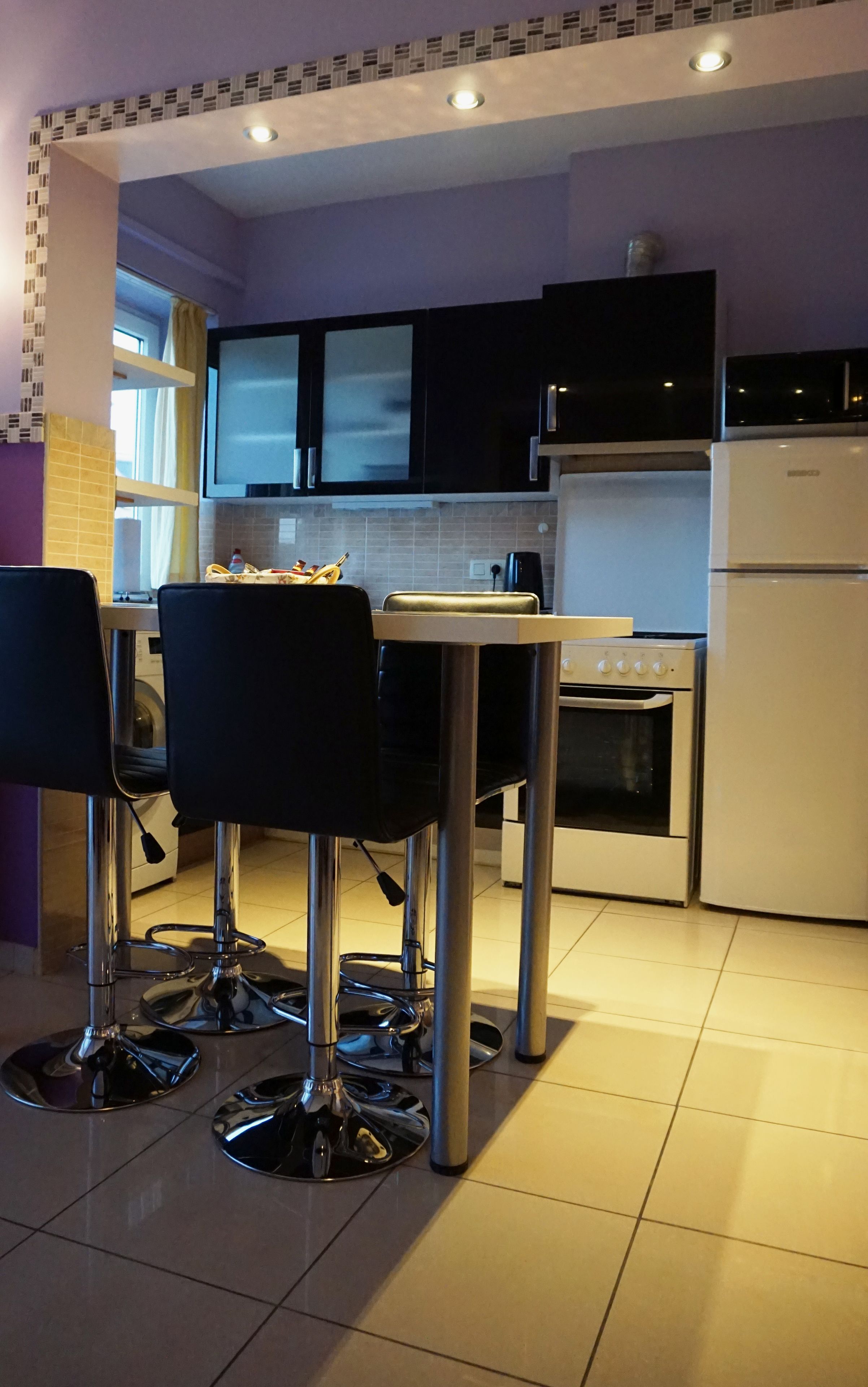 Una cocina compacta con comedor, que incluye una mesa con sillas, un refrigerador, un horno y una lavadora.
