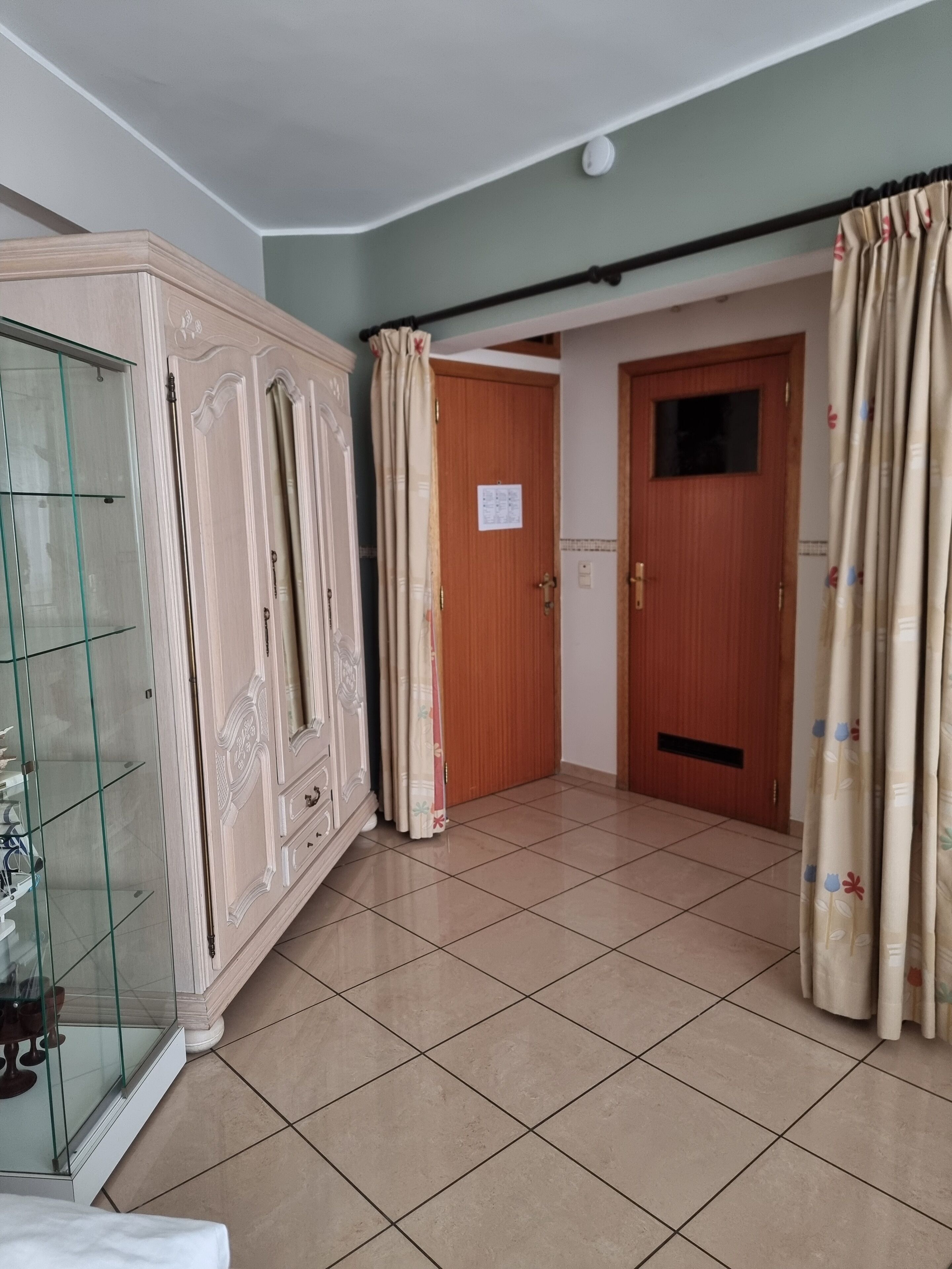 A room with a large wardrobe, a door, and a tiled floor.