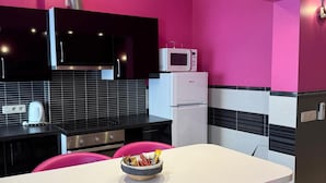 Une cuisine moderne avec des murs roses, une table blanche et des chaises roses.