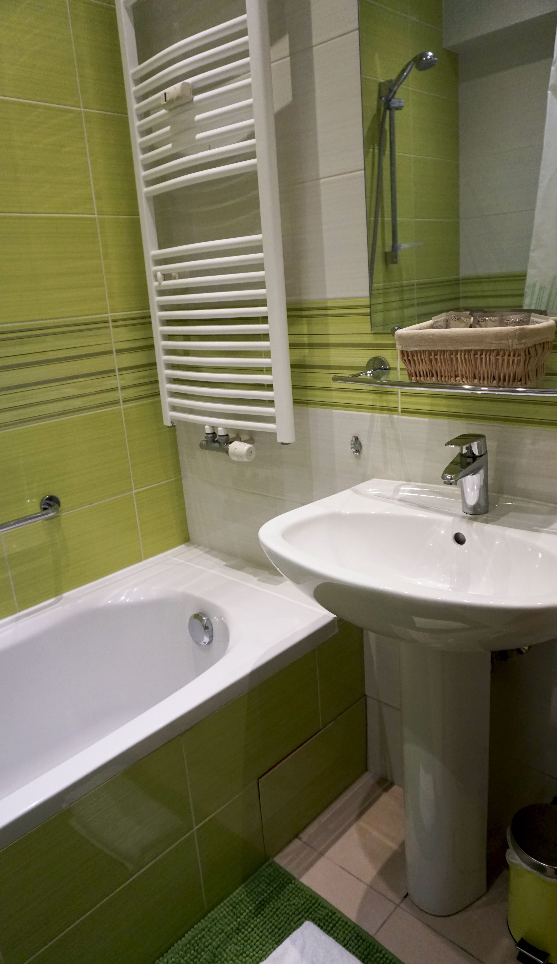 Un baño con bañera, lavamanos, toallero y zona de ducha.