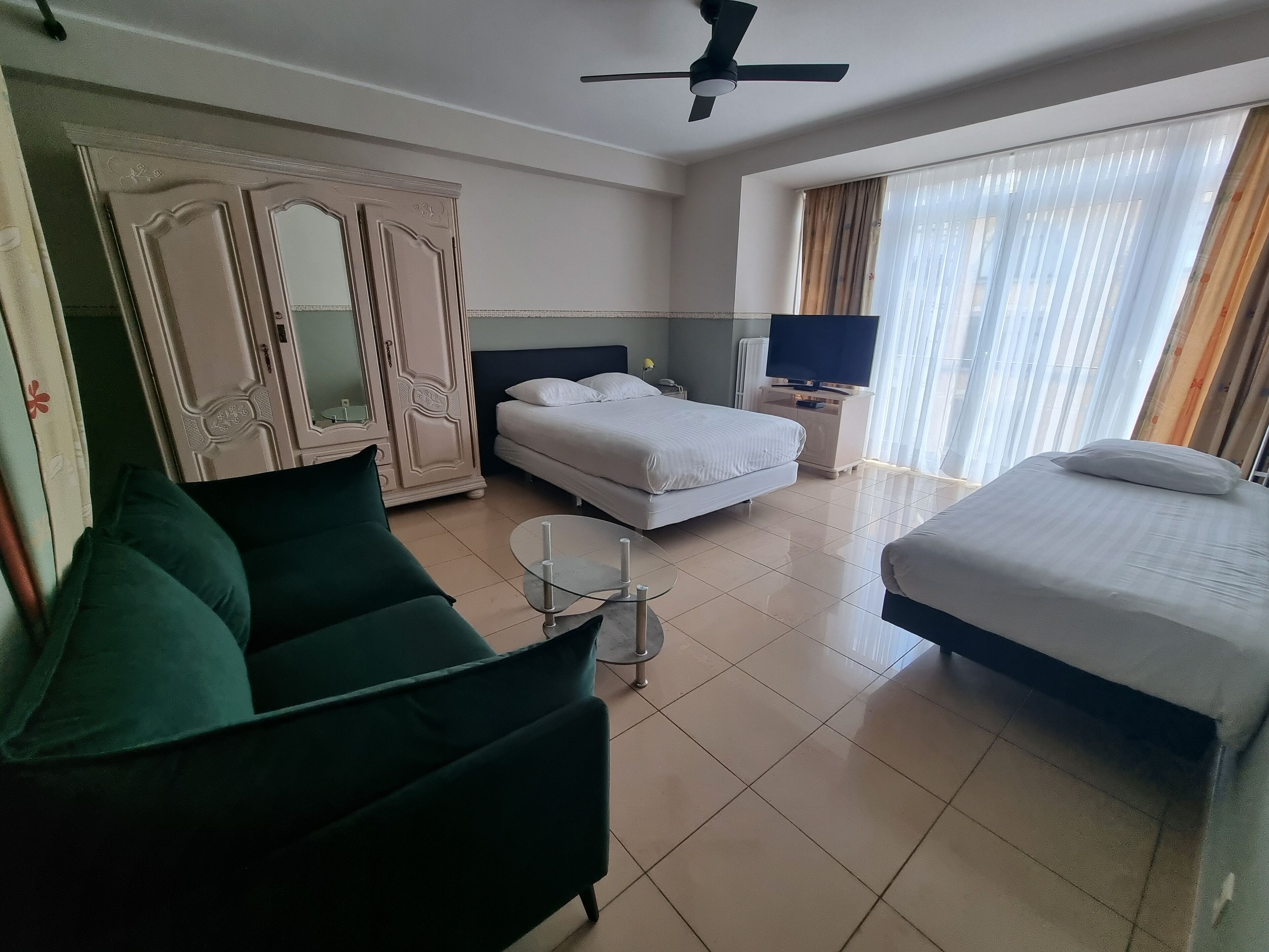 Une chambre d’hôtel avec un lit, un canapé, une télévision et une armoire.