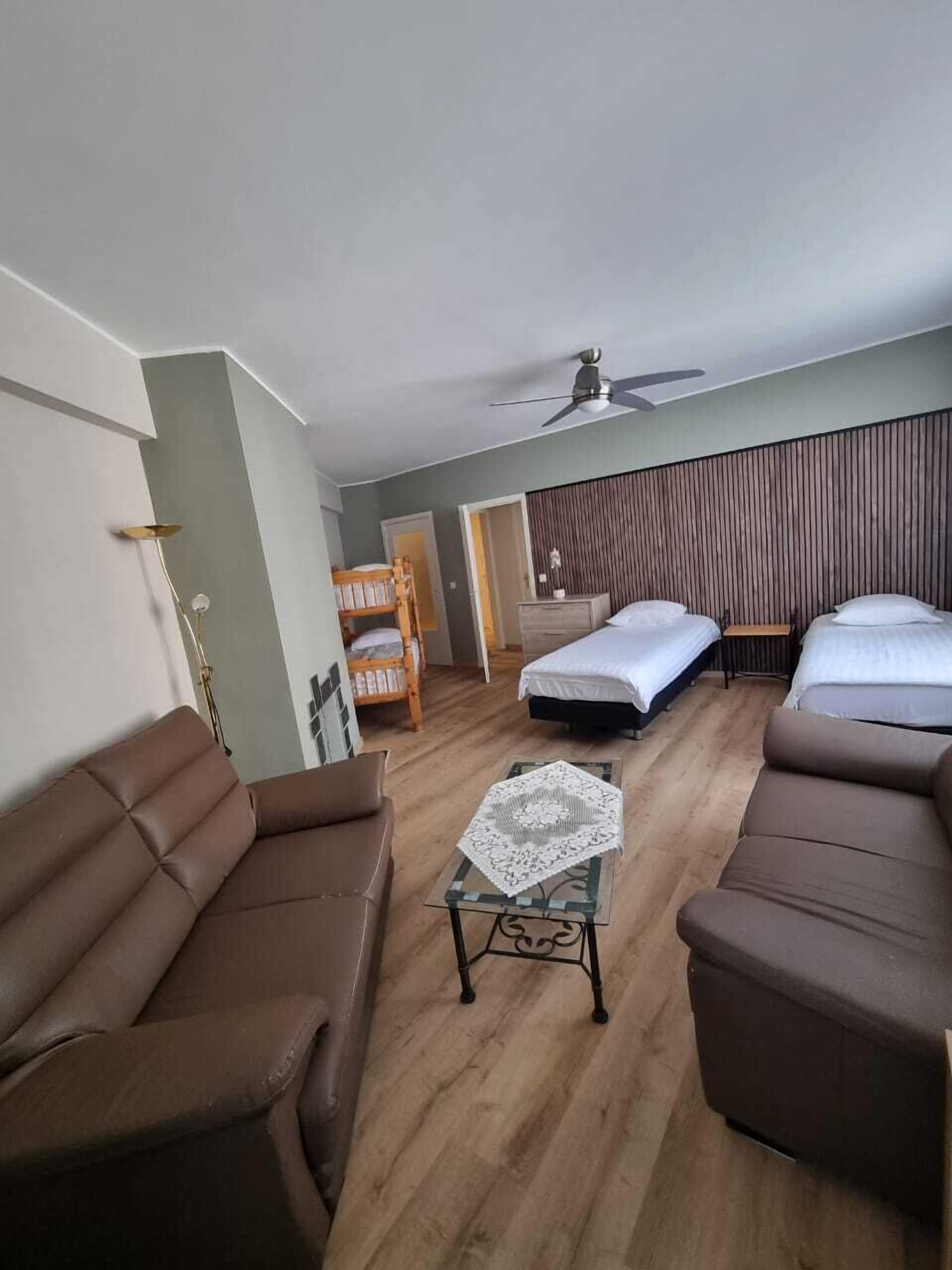A modern living room with two sofas, a coffee table, and a bed with a wooden headboard.