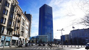 A modern high-rise building with a glass facade, surrounded by older brick buildings with storefronts. - Aparthotel Résidence Bara Midi (Brussels)