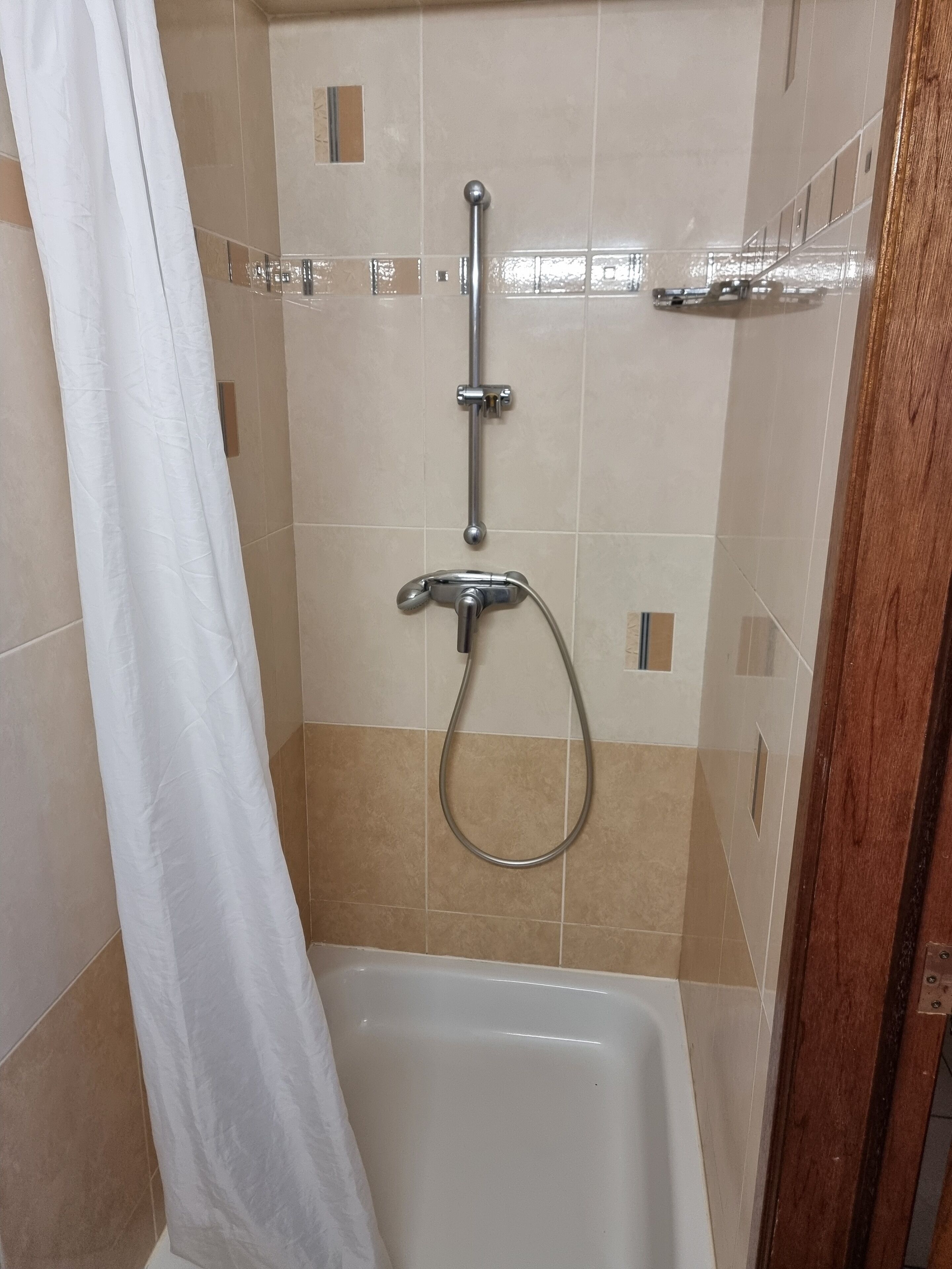 A shower area with a bathtub, a showerhead, and a curtain.