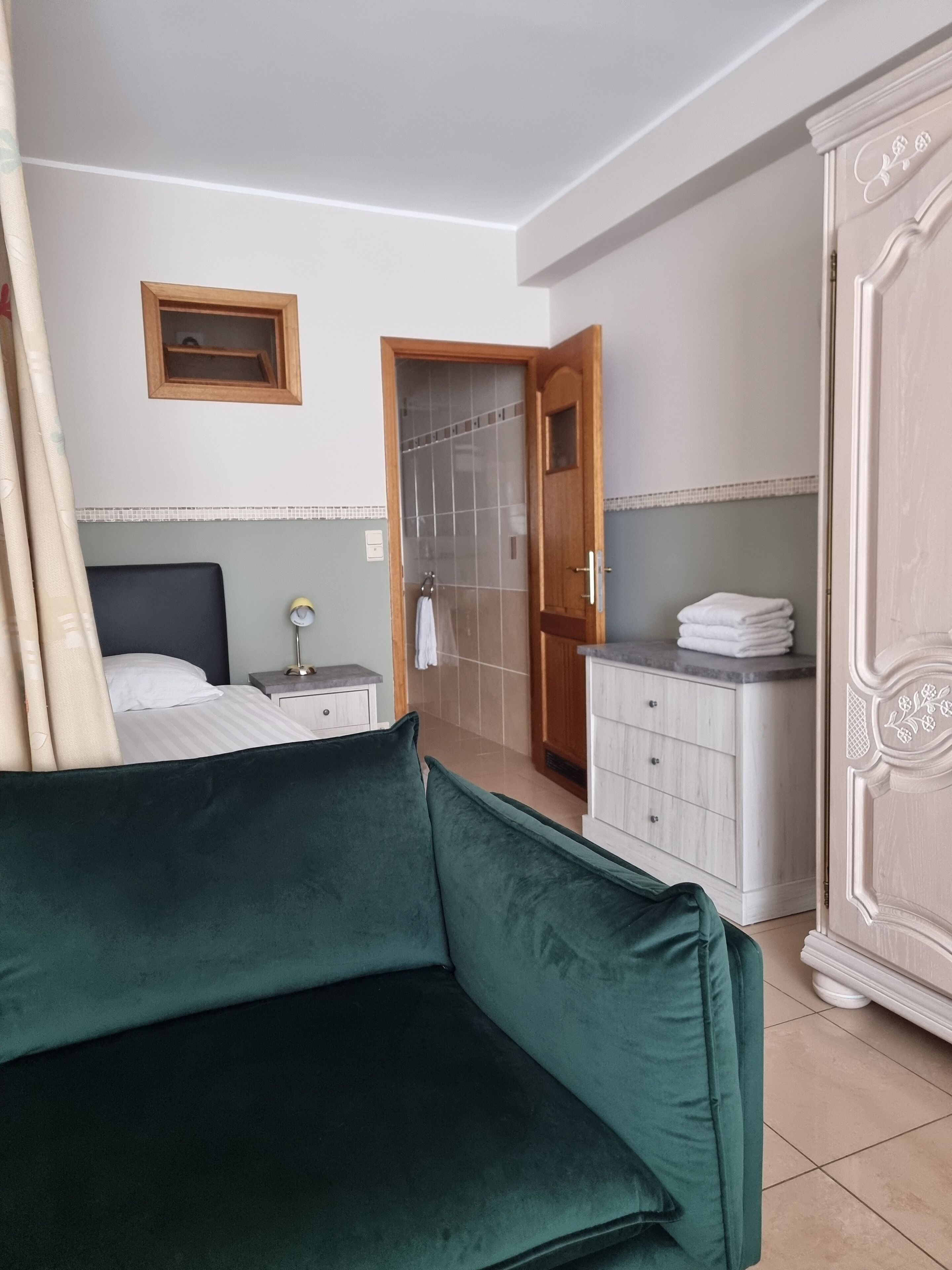 Una habitación de hotel con cama, mesita de noche, cómoda y armario.