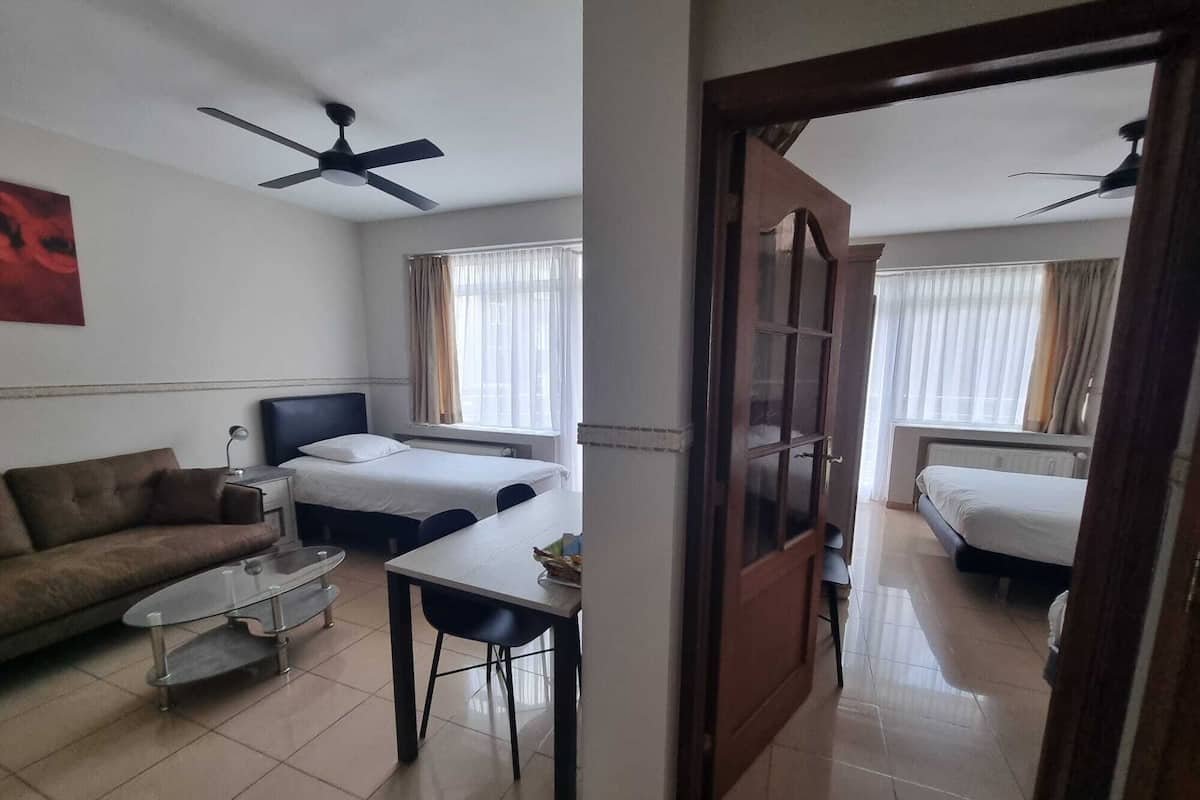 Habitación de hotel con cama, sofá, mesa de comedor y ventilador de techo.
