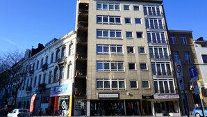 Un immeuble à plusieurs étages, doté de différents commerces, notamment un centre de réparation et un logement.