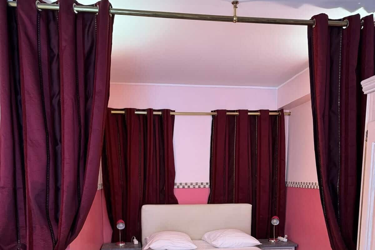 Un dormitorio con cama, dos mesitas de noche y cortinas rojas.