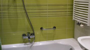 Une salle de bain équipée d’une baignoire, d’une douche et d’un porte-serviettes.