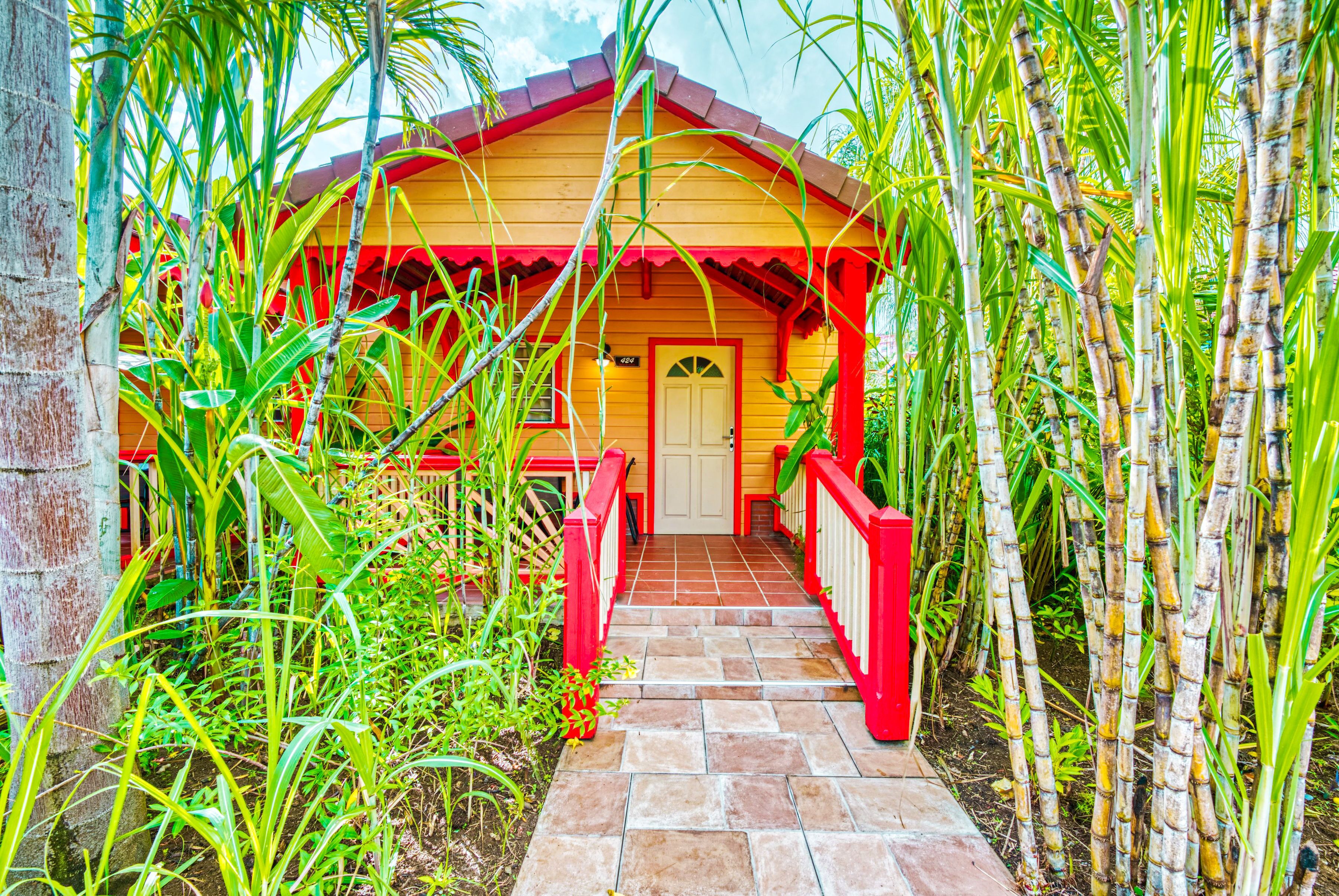 Une maison en bois avec un toit rouge et un chemin dallé menant à une porte blanche.