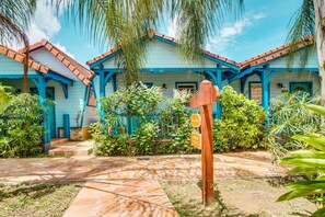 A blue house with a tiled patio and surrounding greenery. - Hôtel Bambou & Spa (Trois-Ilets)