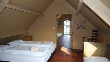 Een slaapkamer met een groot bed, een stoel, een kleine tafel en een televisie achterin.