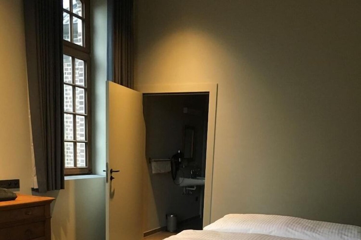 A bedroom with a bed, a dresser, and a window with curtains.