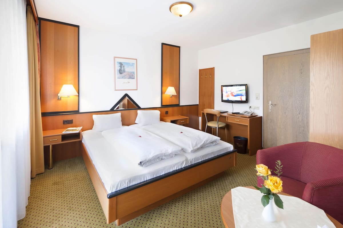 Une chambre d’hôtel avec un grand lit, un bureau avec un ordinateur, une télévision et un canapé rouge.