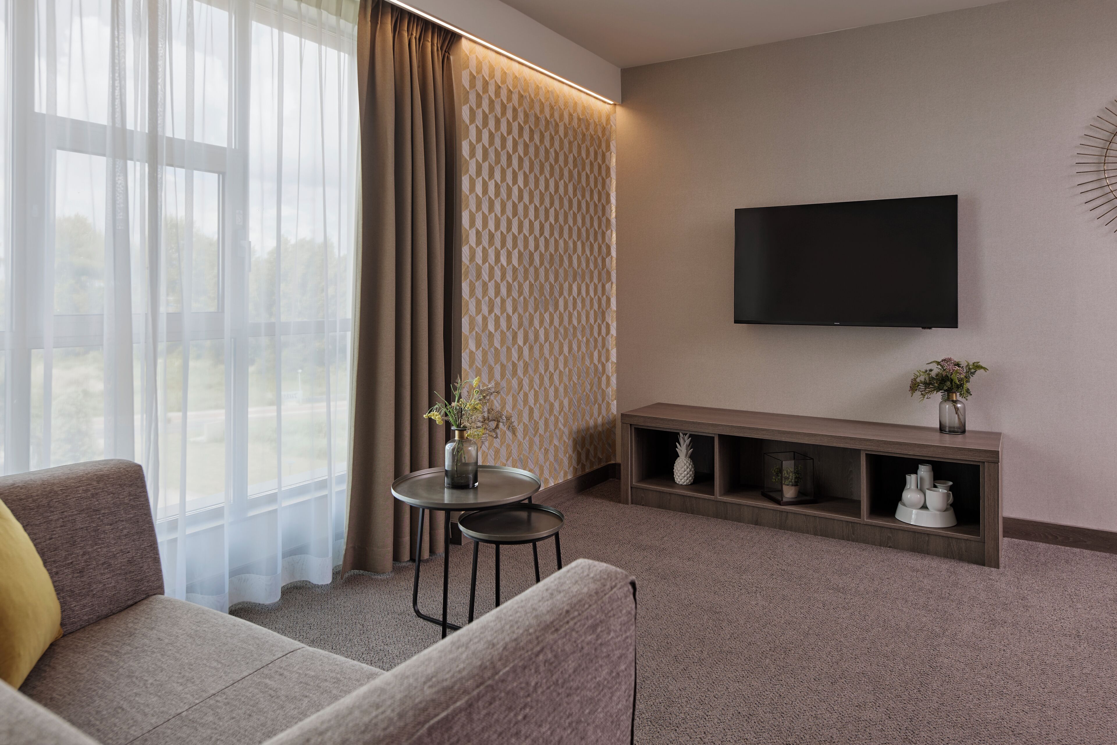 Un salon moderne avec un canapé, une petite table, un téléviseur et une étagère décorative.