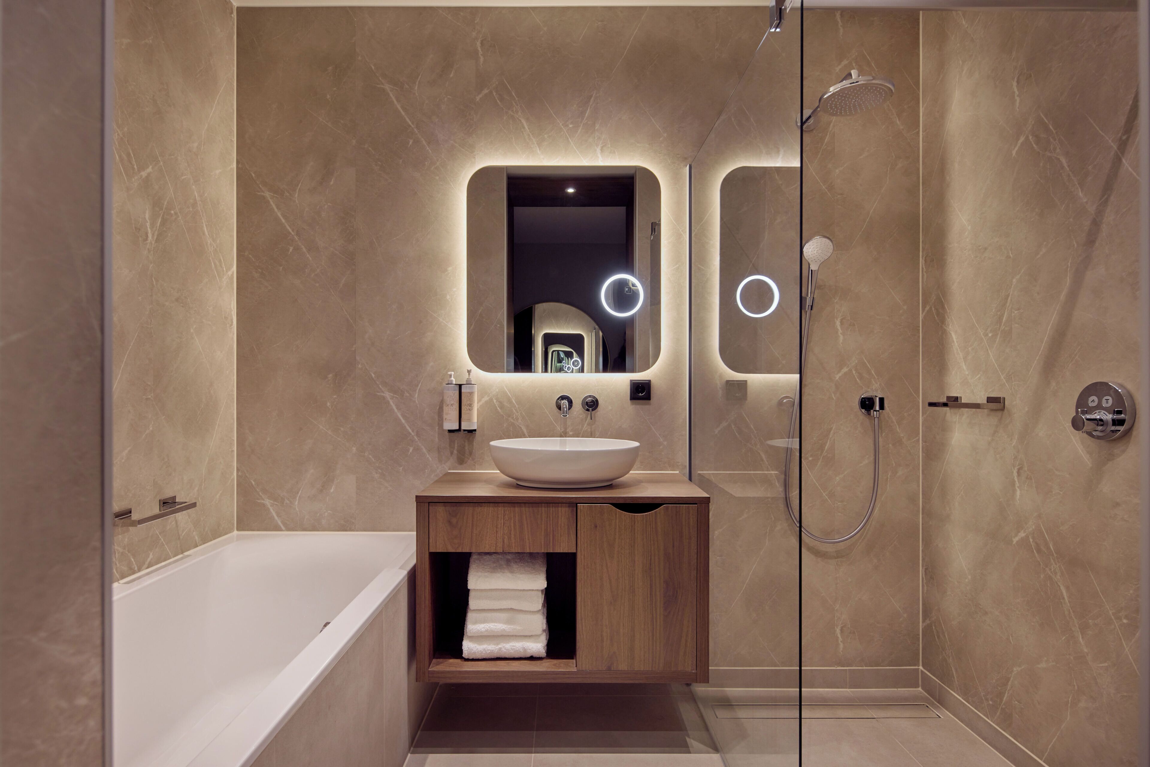 A modern bathroom with a bathtub, a vanity with a mirror, and a shower.