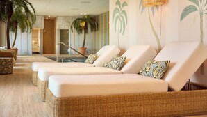 Een wellnessruimte met lounge fauteuils, een zwembad en decoratieve muurkunst.