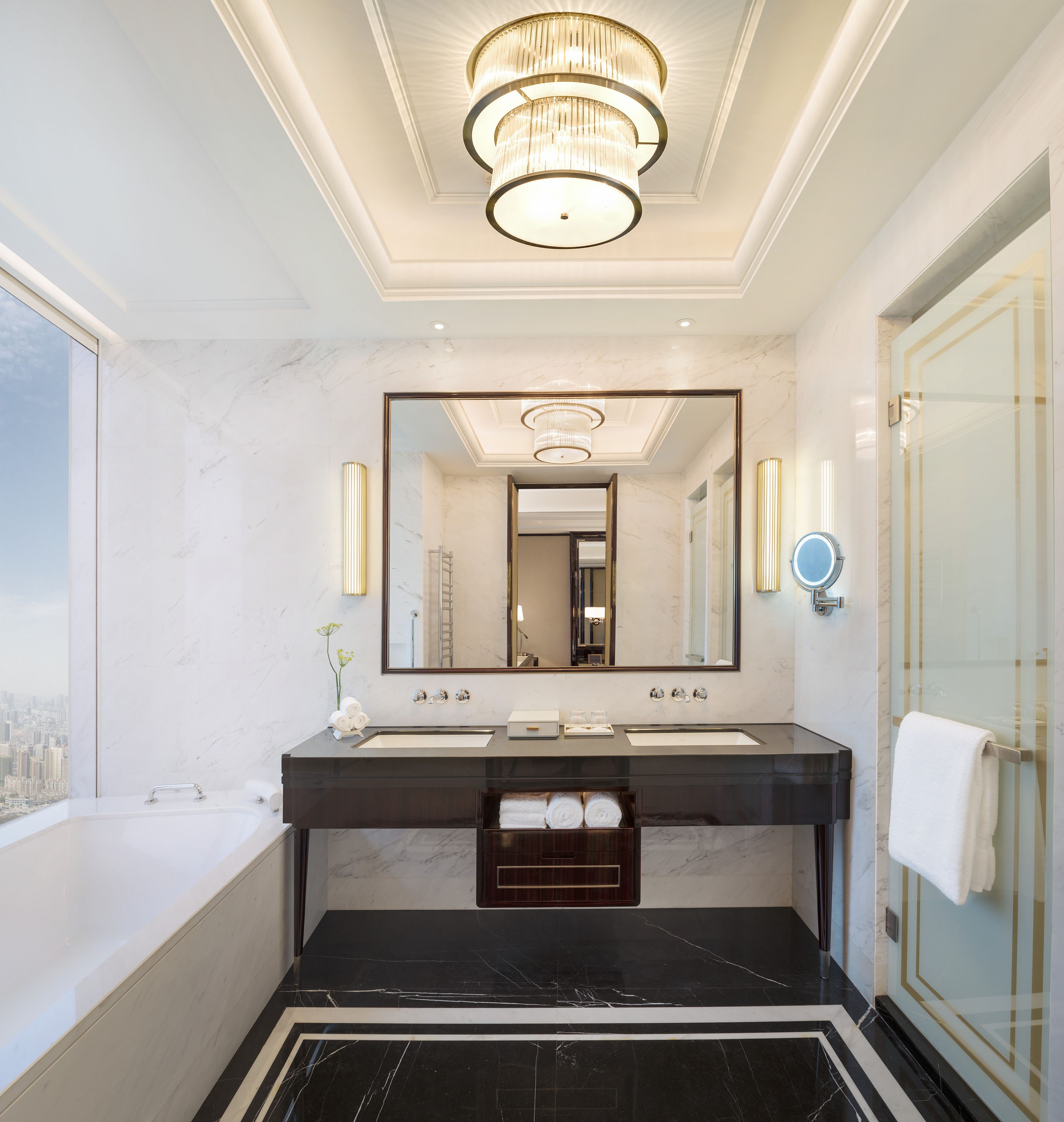 A modern bathroom with a large mirror, two sinks, a bathtub, and a glass shower enclosure.
