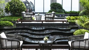 A serene indoor garden with a tiered water feature, wicker furniture, and lush greenery. - The St. Regis Changsha (Changsha)