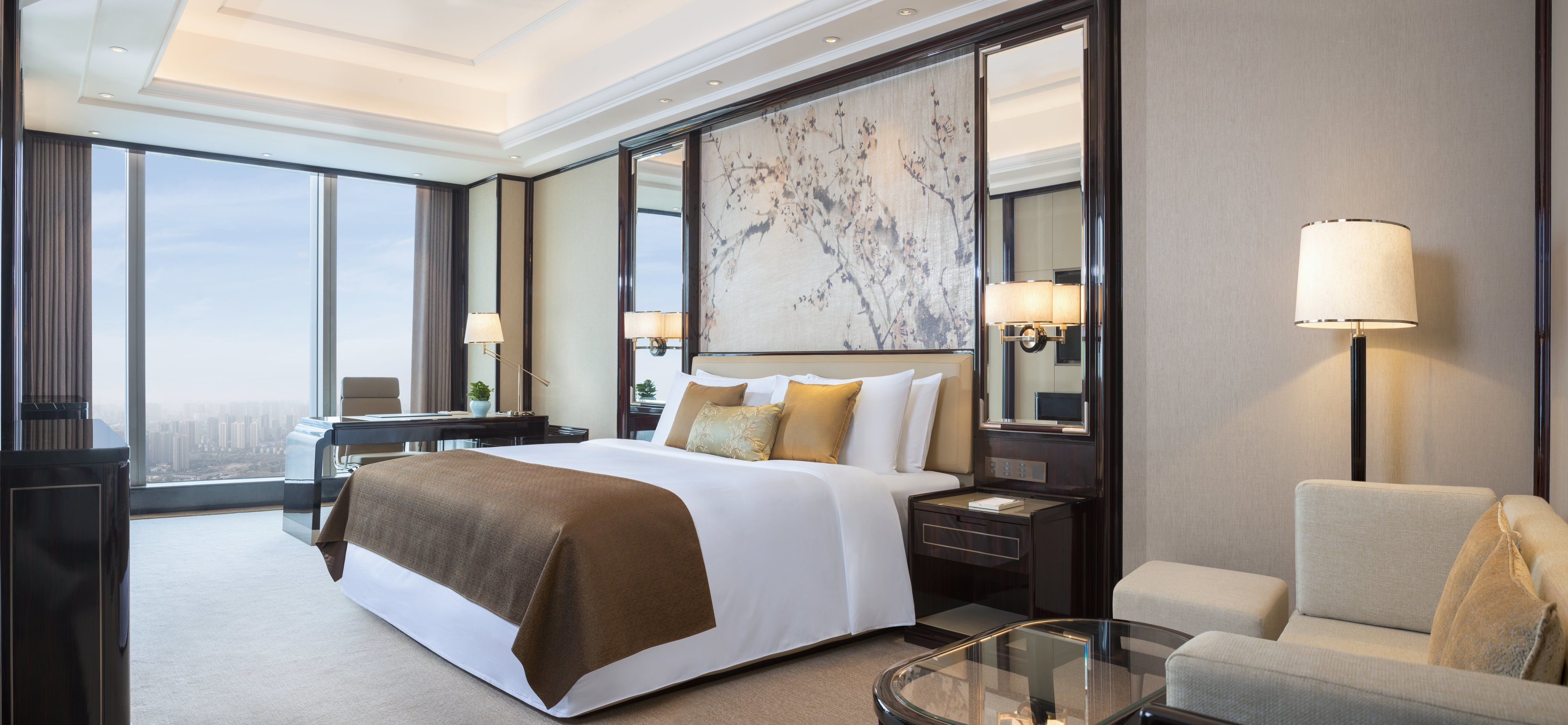 Une chambre d’hôtel spacieuse, dotée d’un grand lit, d’un coin salon, d’un bureau et offrant une vue sur la ville.
