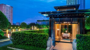 A modern building with a traditional entrance, a well-maintained garden, and a view of a busy road. - The St. Regis Changsha (Changsha)