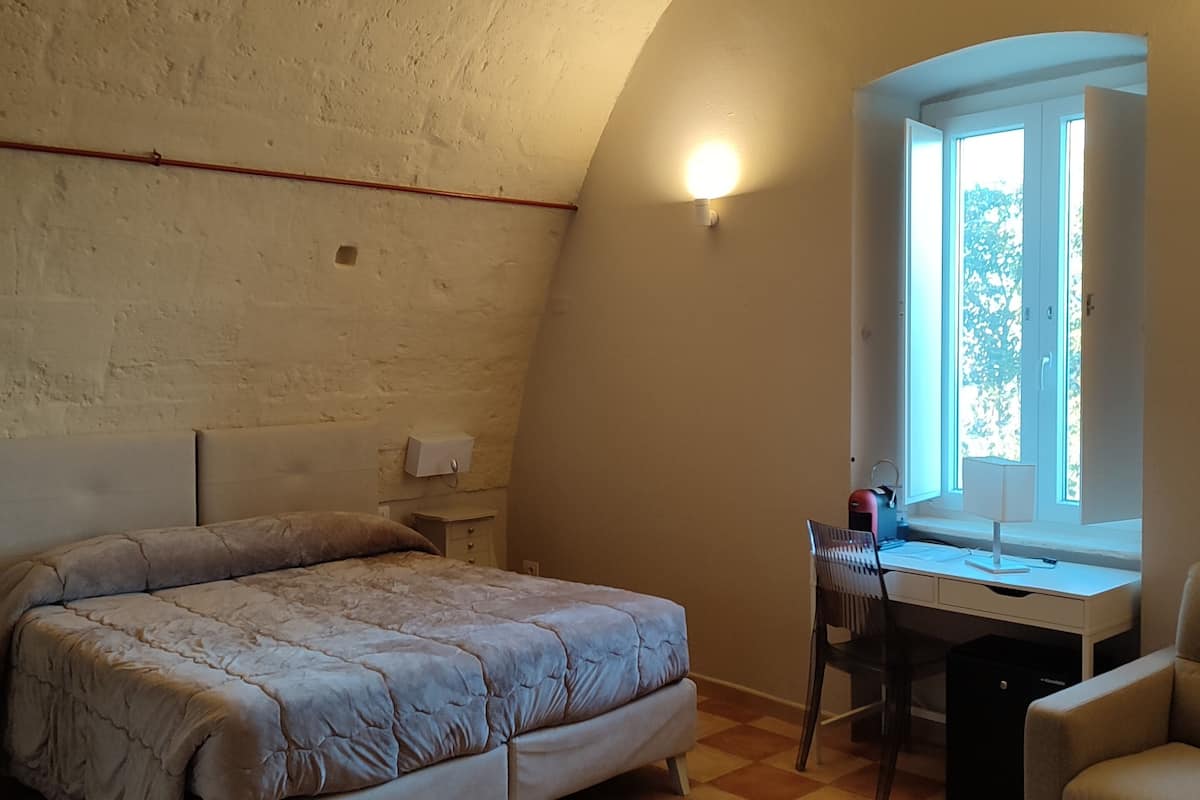 A bedroom with a bed, a desk, and a chair.