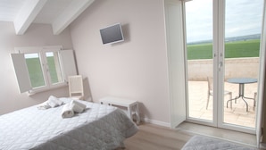 Un dormitorio con dos camas, un televisor en la pared y un balcón con mesa y sillas.