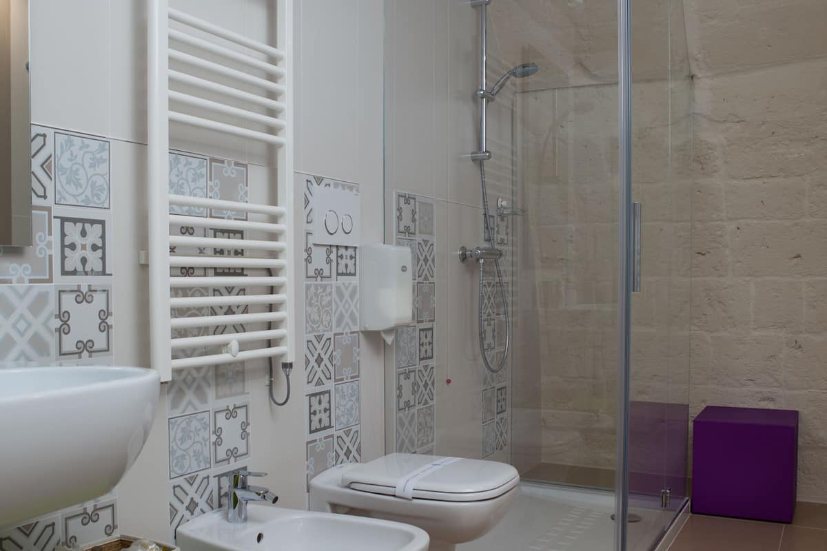 A modern bathroom with a glass shower enclosure, a white sink, a bidet, and a toilet.