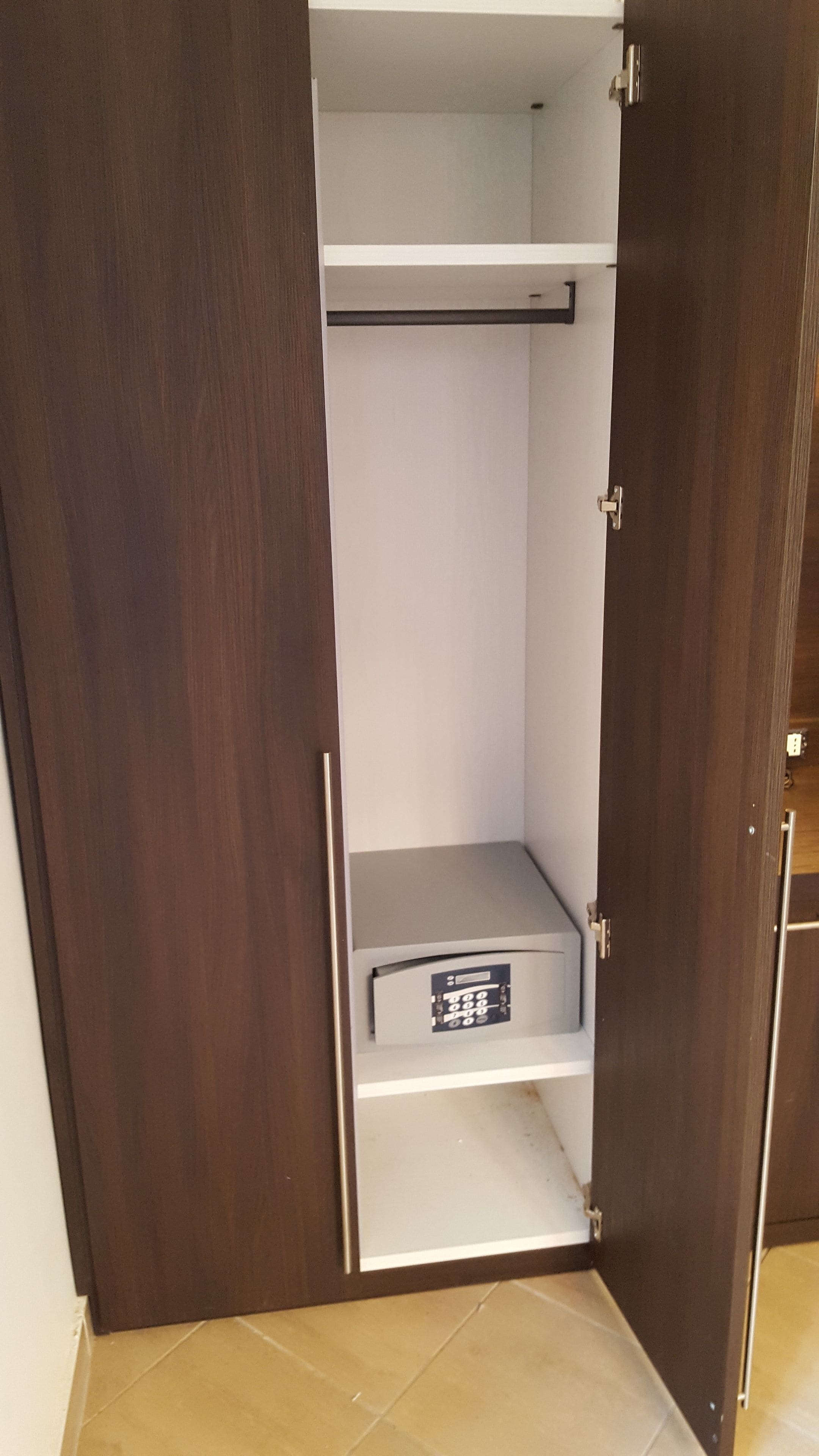A closed wooden wardrobe with a shelf and a hanging rod.